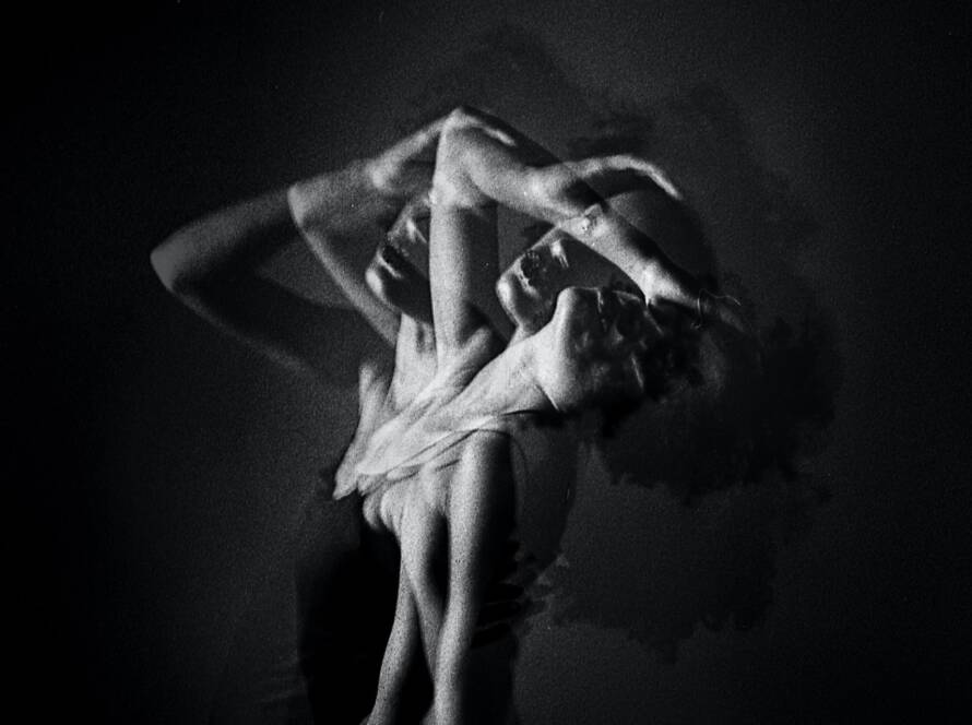 A black and white image featuring a person in a dance pose, captured with a motion blur effect.
