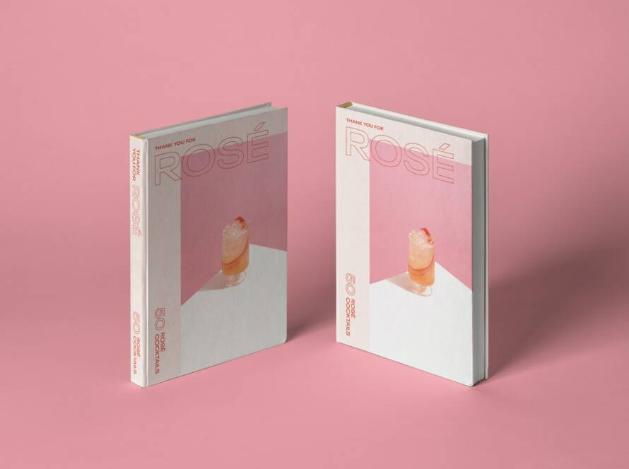 Two cookbooks titled "Rose" with a cocktail image on the front cover, placed on a pink surface.
