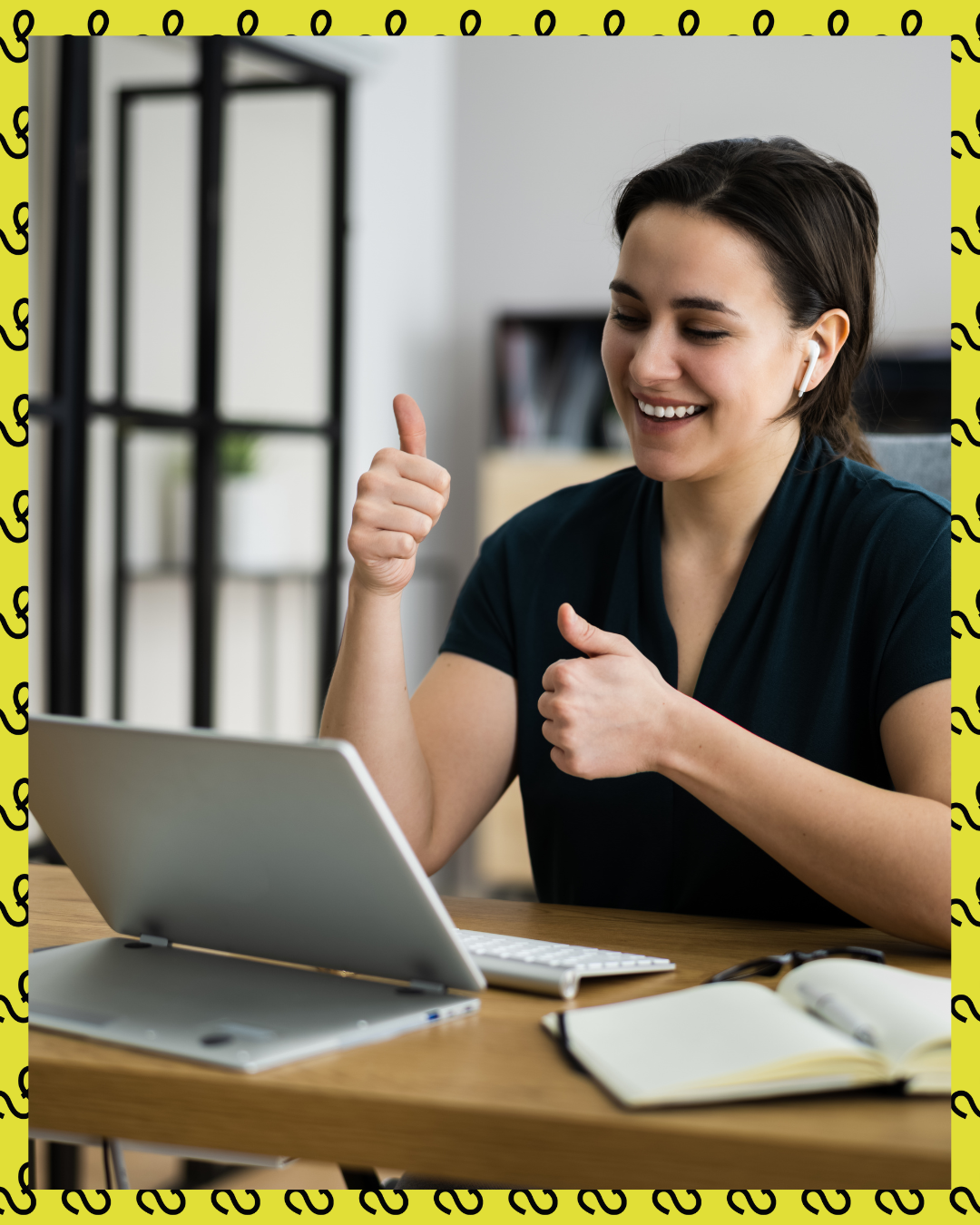 Woman giving thumbs up, smiling during a video call on a laptop with wireless earbuds.