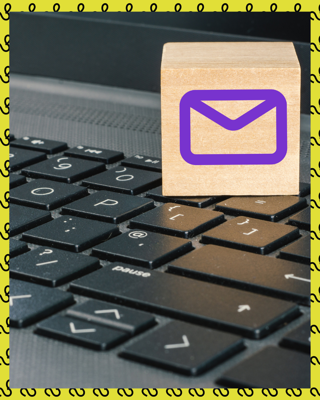 A wooden block with an email symbol sits on a laptop keyboard, suggesting online communication.