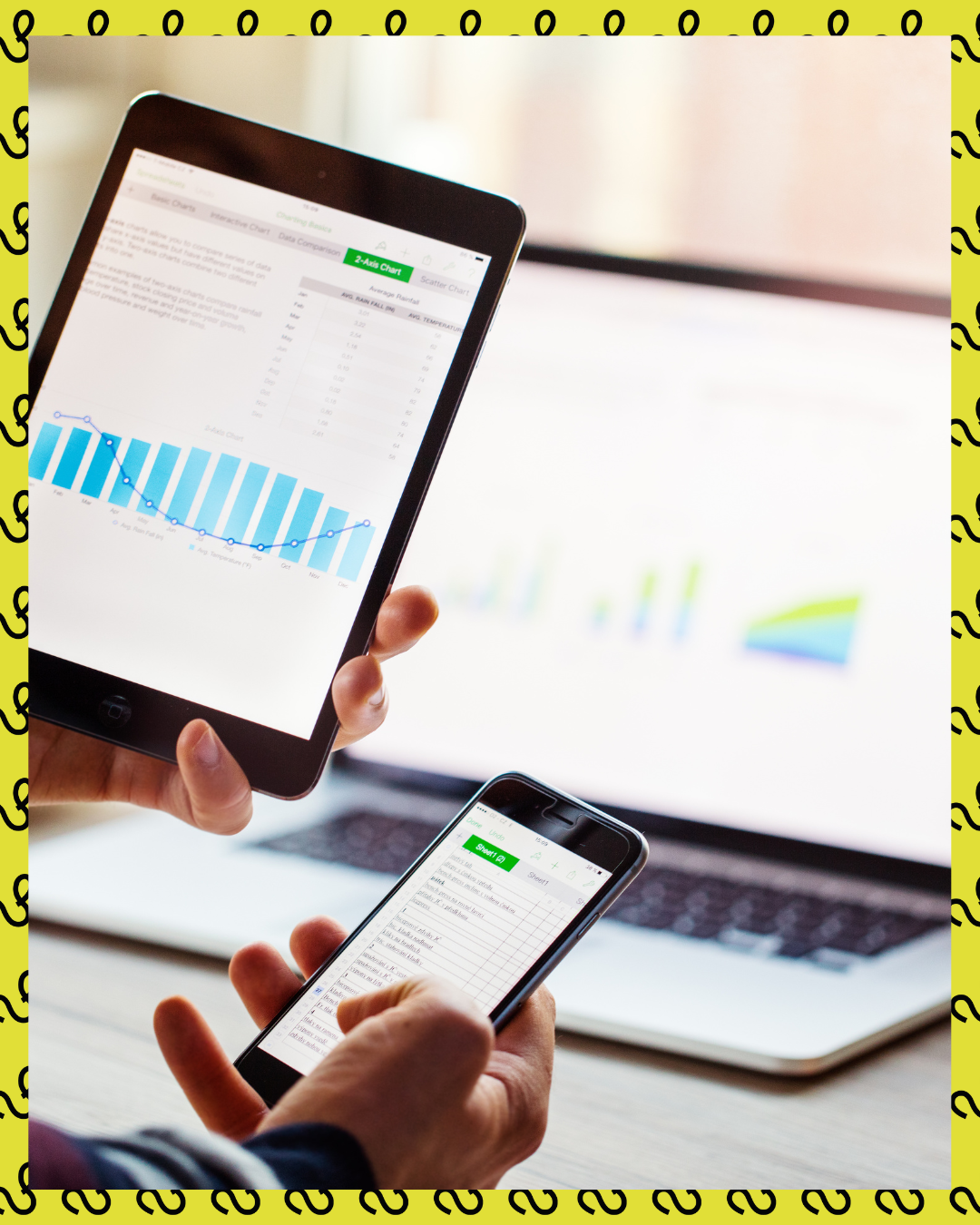 A person uses multiple devices with charts and spreadsheets open.